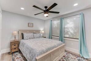 A bedroom with a bed, nightstands, a ceiling fan, and a window with curtains. - *Farmhouse 2/2 Renovated Condo 6 mins from IMG* (Bradenton)