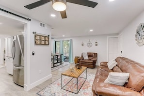 Un salon moderne avec un canapé en cuir marron, une table basse en bois et un ventilateur de plafond.
