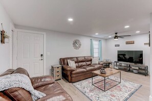 A living room with a brown leather sofa, a coffee table, a TV, and a ceiling fan. - *Farmhouse 2/2 Renovated Condo 6 mins from IMG* (Bradenton)