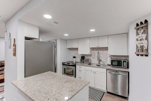 A modern kitchen with white cabinets, stainless steel appliances, and a granite countertop. - *Farmhouse 2/2 Renovated Condo 6 mins from IMG* (Bradenton)