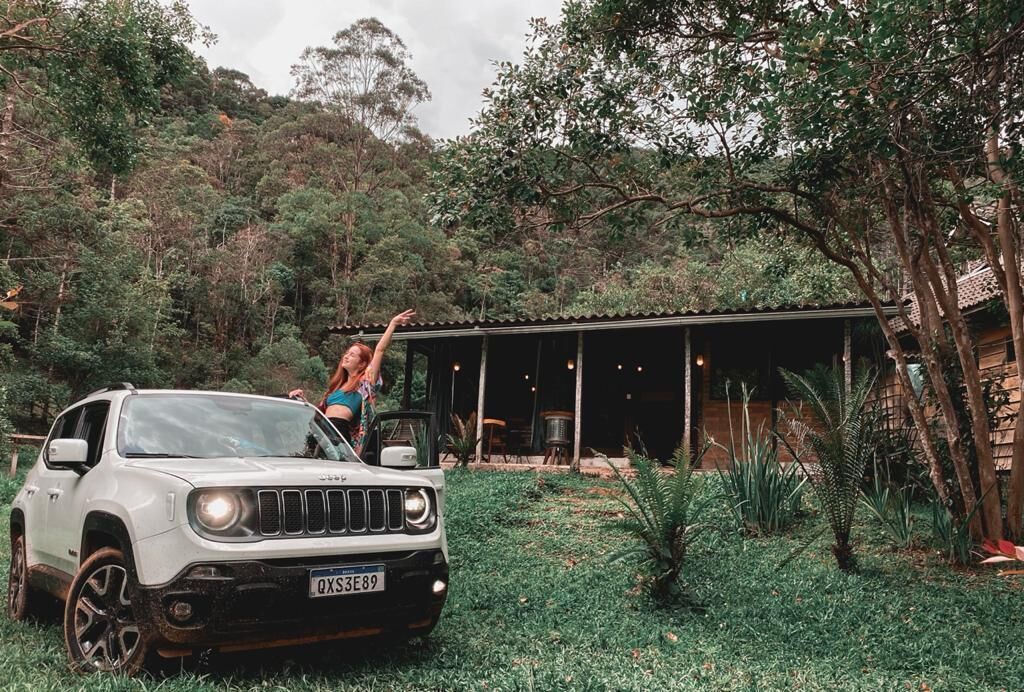 Um SUV branco estacionado em um jardim exuberante, com uma área coberta ao fundo.