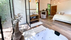 A modern bedroom with a large bed, a fireplace, and a view of the outdoors. - Pousada irreplaceable (Bocaina de Minas)