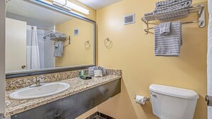 Un baño con lavamanos, espejo, toallero y retrete.