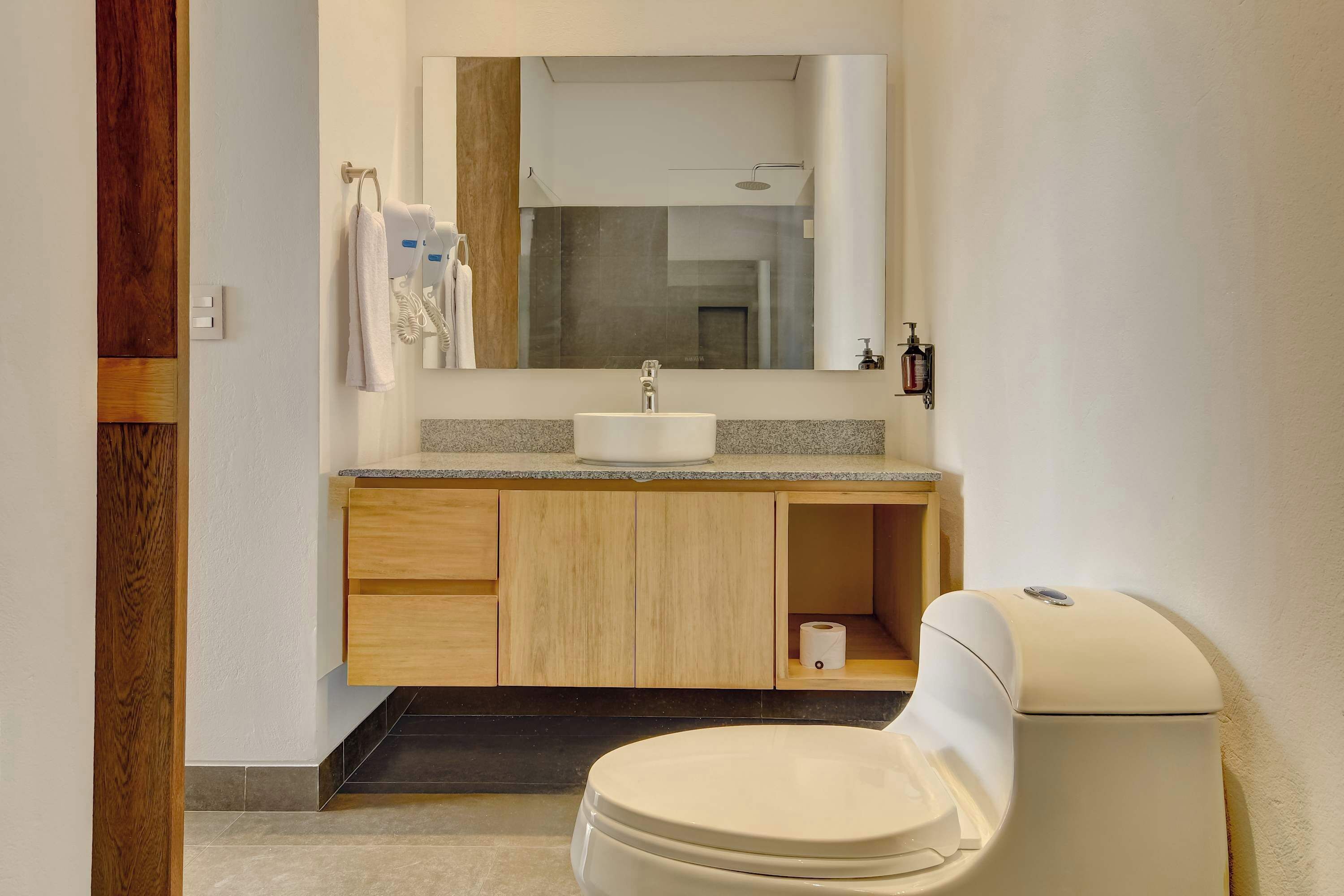 A modern bathroom with a toilet, sink, and mirror.