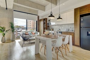 A modern kitchen with a central island, white cabinetry, and a black refrigerator. - w* | Jungle Design 1BR in Parque 93 (Bogotá)