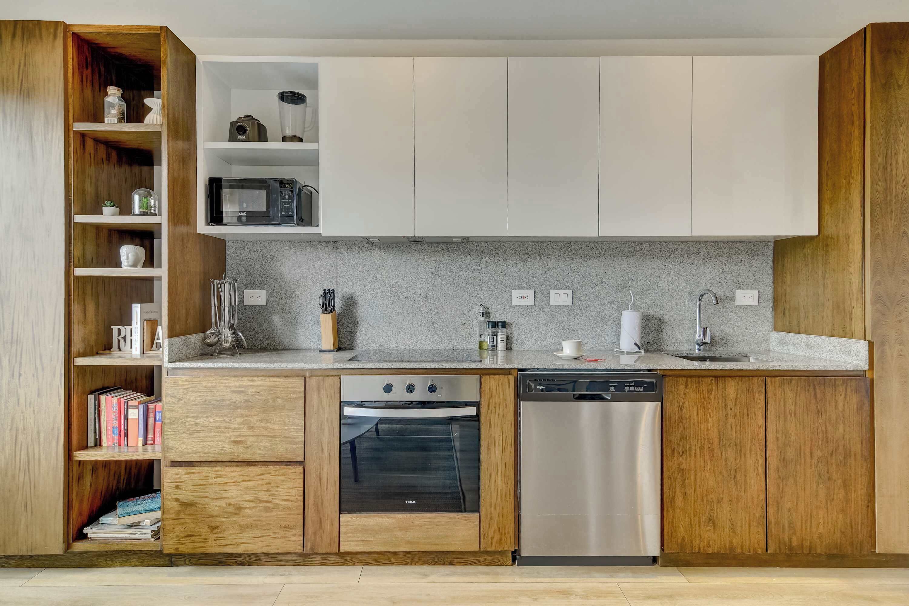 Una cocina moderna con armarios de madera, horno empotrado, lavavajillas y encimera de granito.