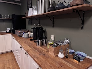 Una encimera de cocina con diferentes utensilios, una cafetera y salero y pimentero.
