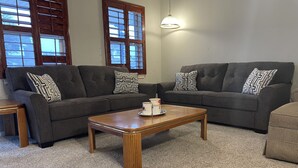 A living room with two dark grey sofas, patterned throw pillows, a wooden coffee table, and a small side table. - 11-Guests/Airport -Minute Away/Pet-Welcome/4-BDR/2-FBA/5-QBED! (Oklahoma City)