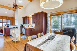 A spacious kitchen with wooden cabinets, a dining area with a table, and a large window with a view of trees. - The best sunset views are at Mountain View Retreat! (Canaan Valley)