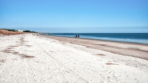 Une vaste plage de sable fin, sous un ciel bleu et dégagé.