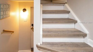 Un escalier avec des marches en bois et un luminaire placé au-dessus de la porte.