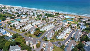 A coastal residential area with multiple houses, a swimming pool, and a view of the ocean.