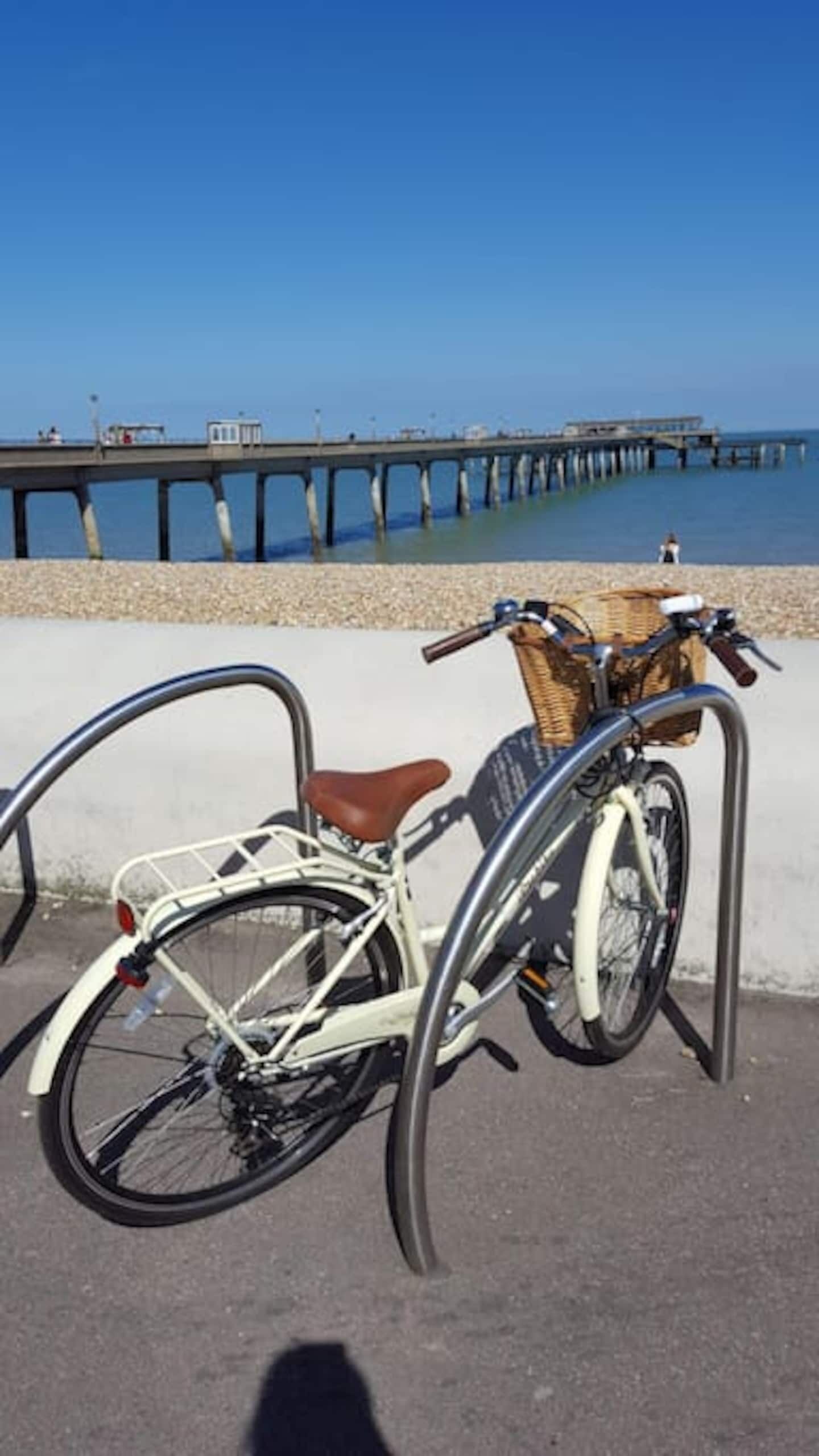 A bicycle parked by a concrete barrier with a view of a pier extending into the water.