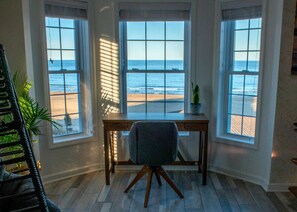 A room with a desk and chair facing large windows overlooking a beach. - Beachfront Getaway, Mermaid Suite, 🐶 💙 (Norfolk)