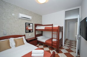 A hotel room with a bunk bed, a single bed, a desk, a chair, a TV, and a door. - D&D Apartment Budva 1 - Apartment with 4 beds (Budva)