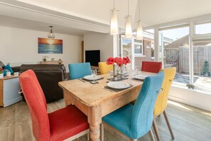 A dining area with a wooden table, colorful chairs, and a view of the outside.