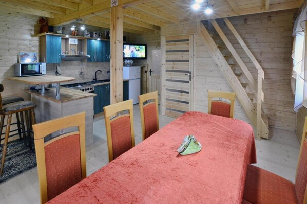 A cozy cabin interior with a dining area, kitchen, and a staircase.