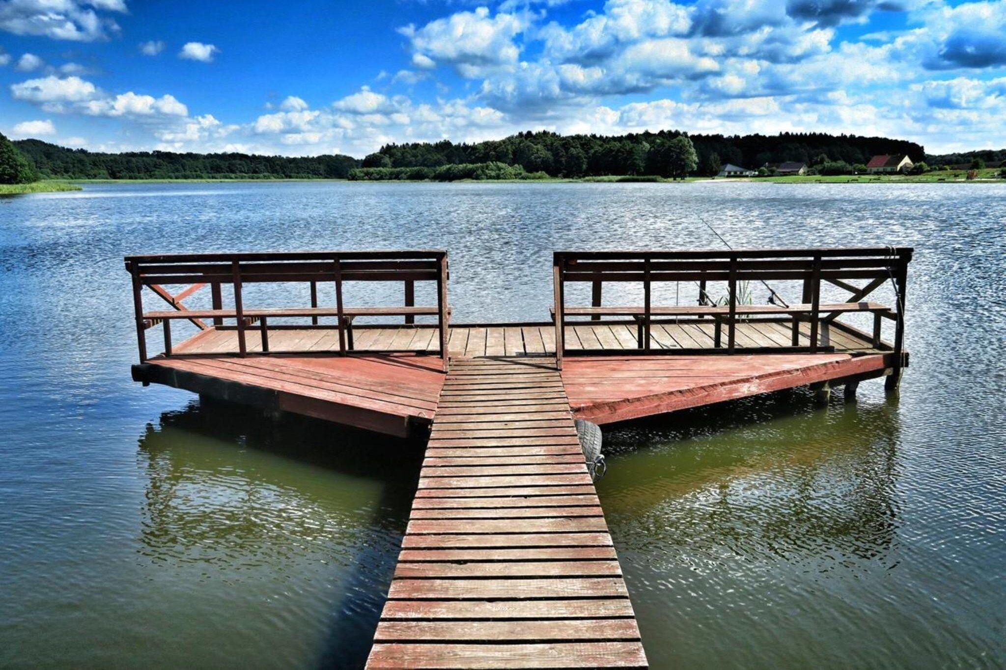Un muelle de madera se extiende sobre aguas tranquilas, bajo un cielo despejado.