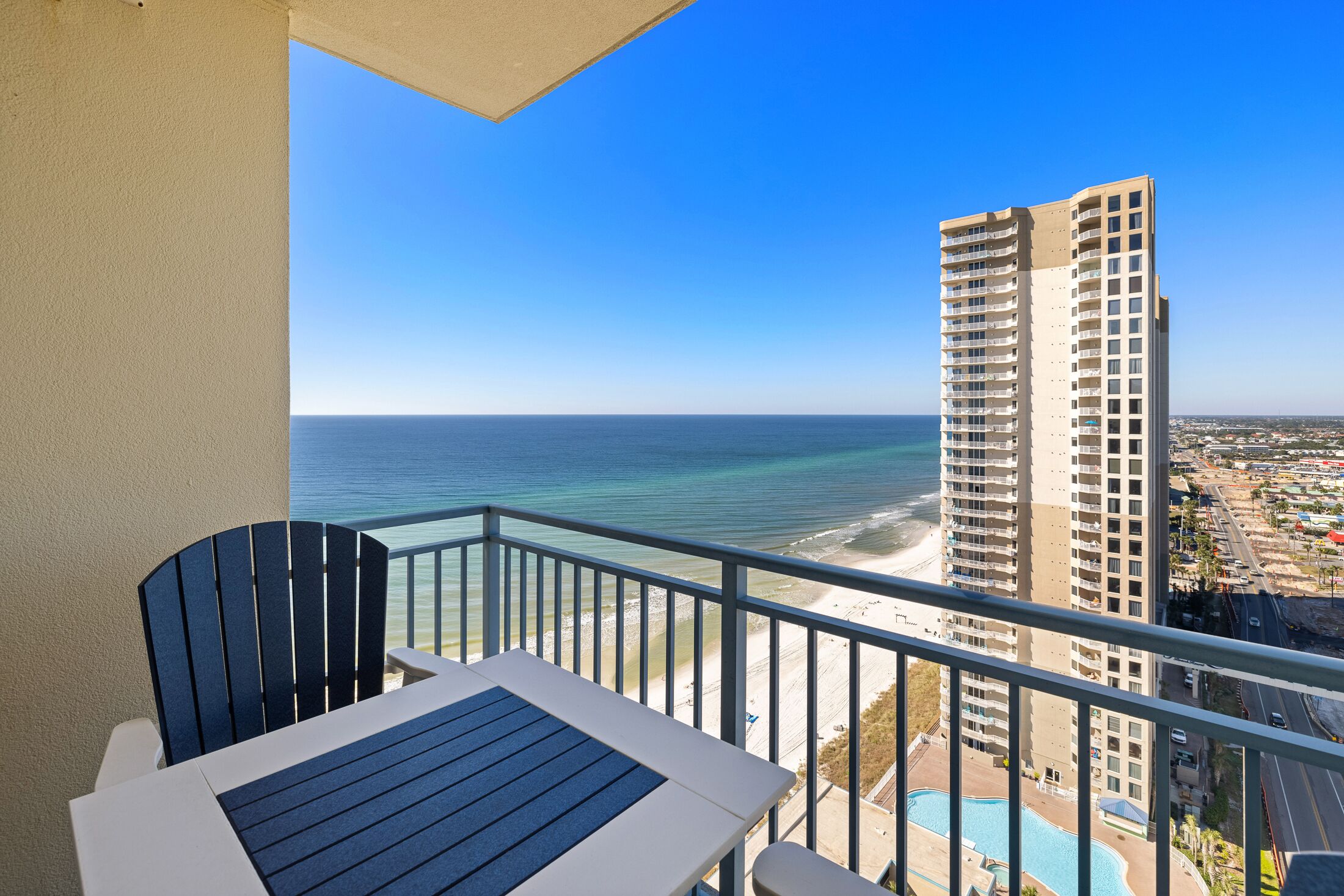 A balcony with a view of the ocean and a tall building.