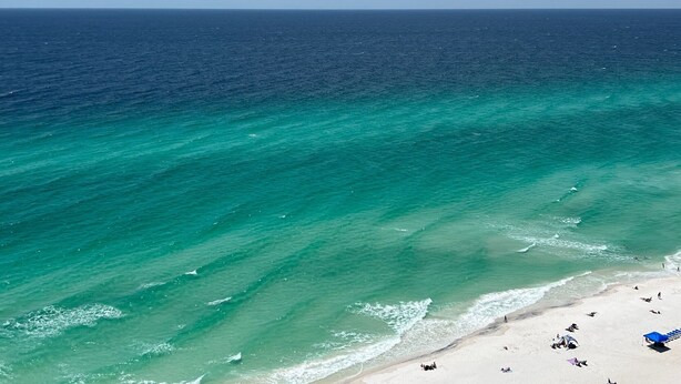 Een strand met helder turquoise water en een zandstrand.