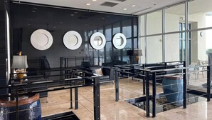 Een moderne lobby met een glazen scheidingswand, zwart meubilair en een waterpartij.
