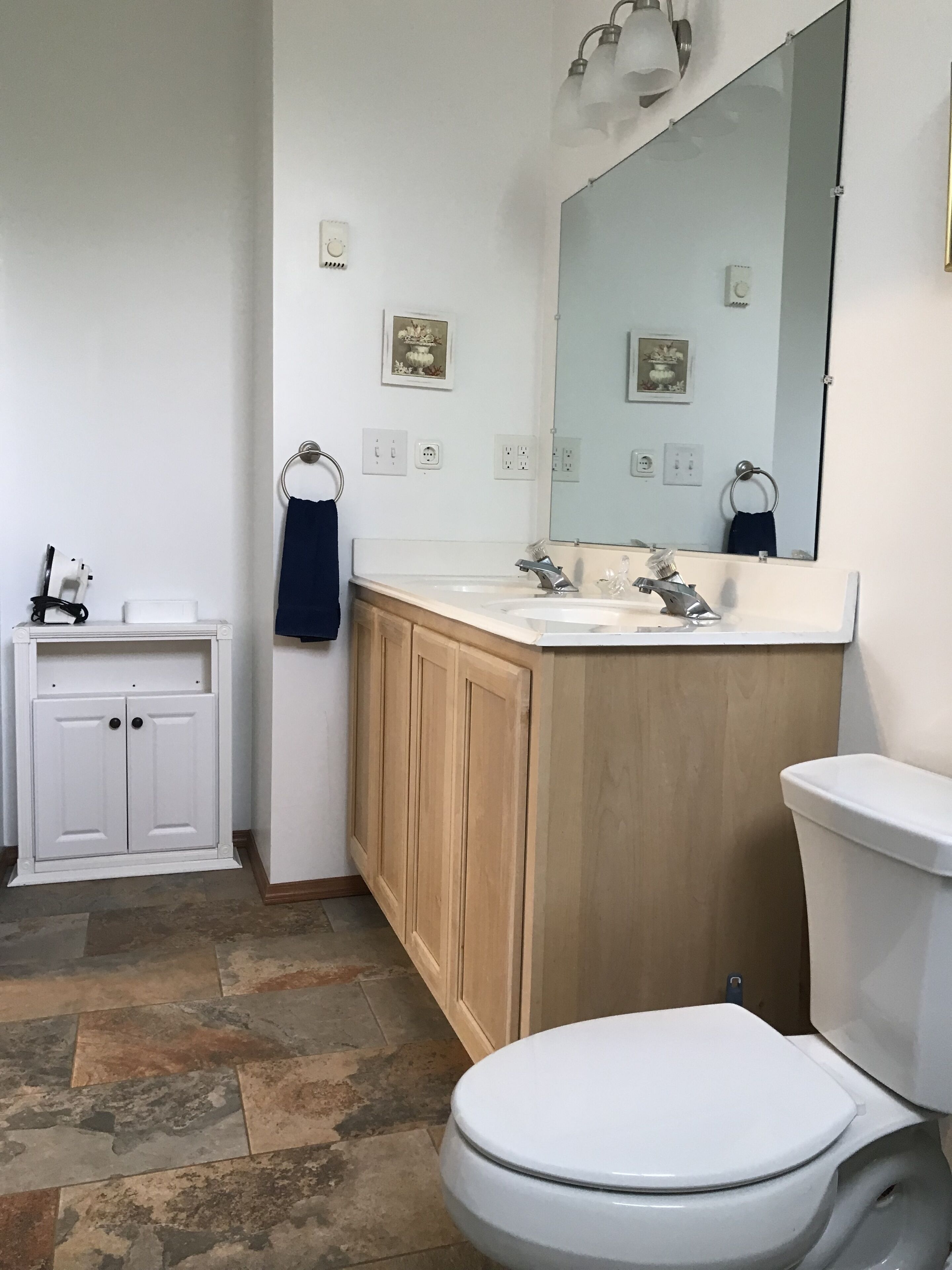 Ein Badezimmer mit Toilette, Waschbecken, Spiegel und Schrank.