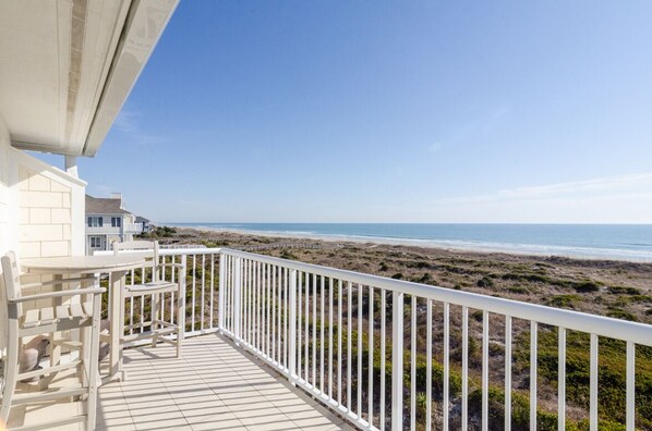 Un balcon avec vue sur la plage et l’océan.