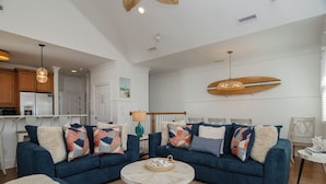 Un salon avec deux canapés, une table basse et une décoration murale représentant une planche de surf.