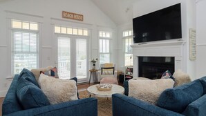 Un salon avec une cheminée, un téléviseur et une pancarte sur laquelle on peut lire « MAISON DE VACANCES AU BORD DE LA MER ».