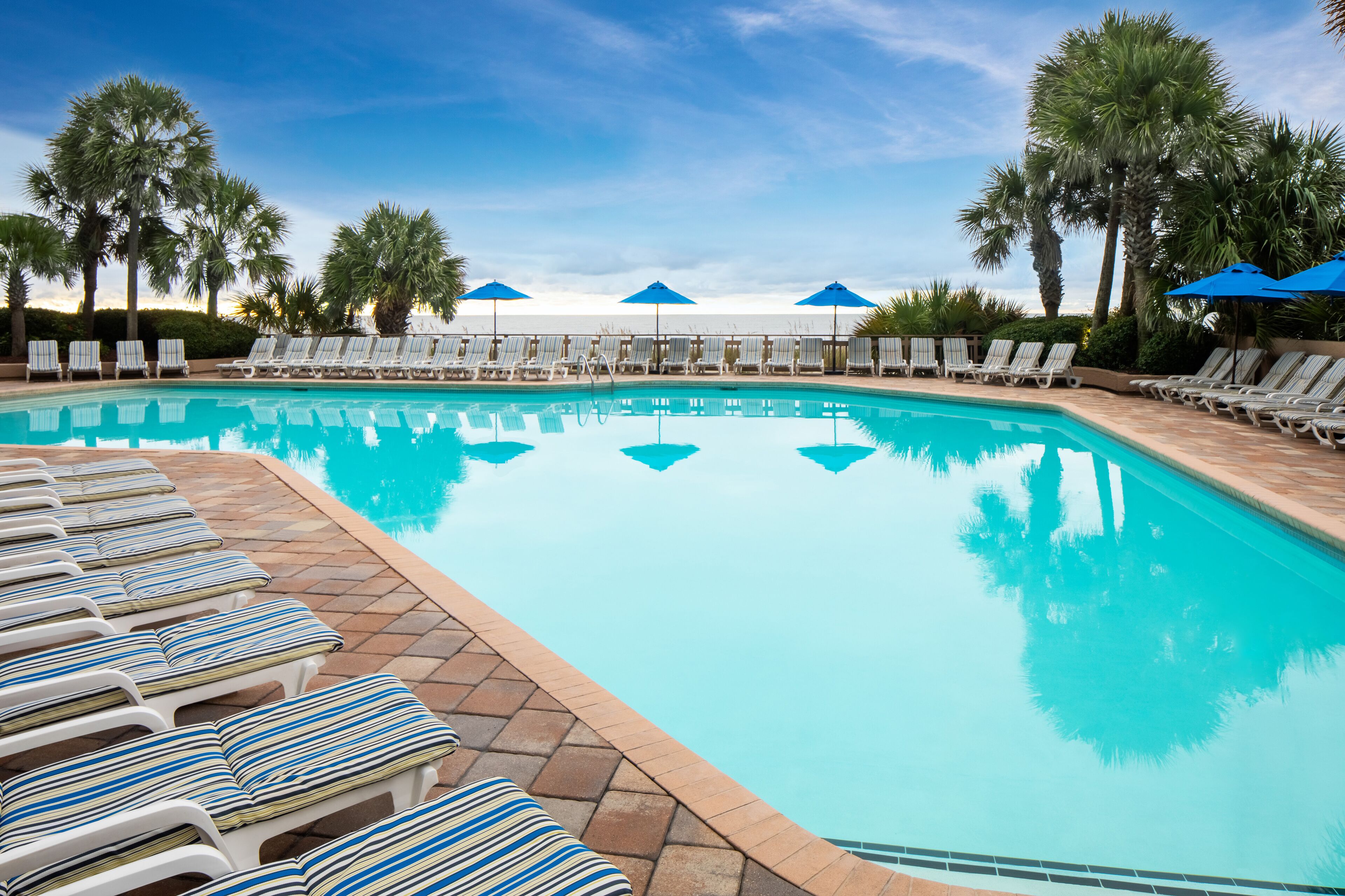 A swimming pool with lounge chairs and umbrellas.