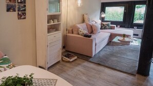 Una sala de estar acogedora con un sofá, un mueble aparador y una mesa de comedor con una planta.