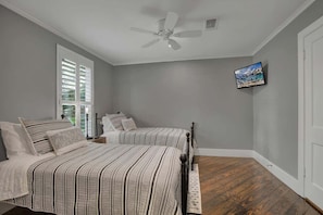 A bedroom with two beds, a ceiling fan, a TV on the wall, and a window with blinds. - Dtown Drippin With New Pool! (Dripping Springs)