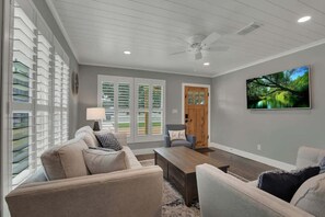 A living room with a sofa, coffee table, and a television mounted on the wall.