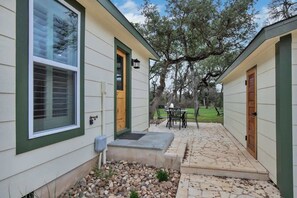A house with a stone patio, a wooden door, and a window with blinds.