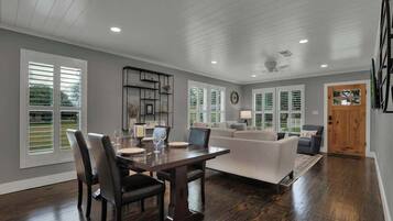 A spacious living area with a dining table, chairs, a sofa, and a coffee table.