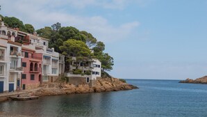 Un bâtiment situé sur la côte, doté de nombreux balcons et bordé d’une plage rocheuse.