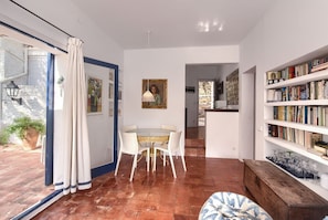A spacious room with a dining area, a bookshelf, and a view of the outside.