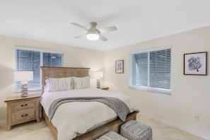 A bedroom with a bed, nightstands, a ceiling fan, and two windows with blinds. - Steps to the beach with heated pool in Old Naples, FL! (Naples)