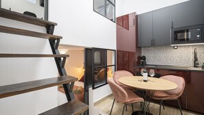 A modern kitchen with dark cabinets, a microwave, and a round table with pink chairs.