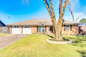A two-story house with a garage, a front yard with a tree, and a brick exterior. - Beautiful home in Houston Memorial, Galleria Area (Houston)