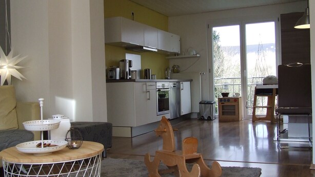 A modern kitchen with white cabinets, a stainless steel range, and a dining area with a round table and a decorative anchor. - Hochwald vacation apartment - in the heart of the Saarland (Quierschied)