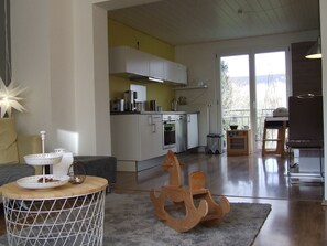 A modern kitchen with white cabinets, a stainless steel range, and a dining area with a round table and a decorative anchor.