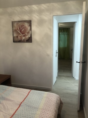 Un dormitorio con una cama, un cuadro de una rosa y una puerta que da a otra habitación.
