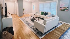 Un salón amplio con un sofá blanco, una mesa de centro y un ventilador de techo.