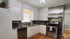 Una cocina moderna con armarios blancos, electrodomésticos de acero inoxidable y piso de madera.