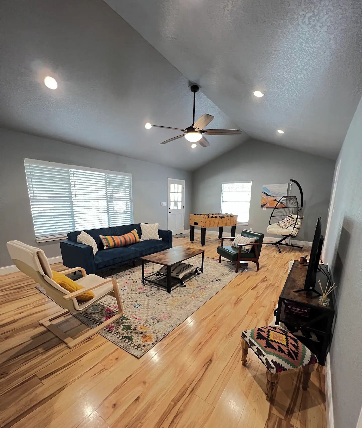 A spacious living room with a ceiling fan, a sofa, a coffee table, and a television.
