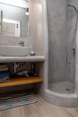 A bathroom with a white sink, a shower, and a mirror above the sink.