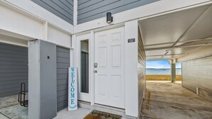 A coastal property with a white door, a welcome sign, and a view of the sea.