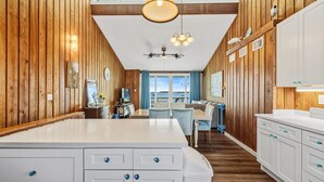 A spacious kitchen with wooden paneling, a large island with drawers, and a view to the outside.
