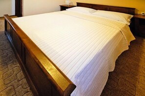 A neatly made bed with a wooden frame and white linens. - Villa in Starigrad near Paklenica National Park (Starigrad Paklenica)